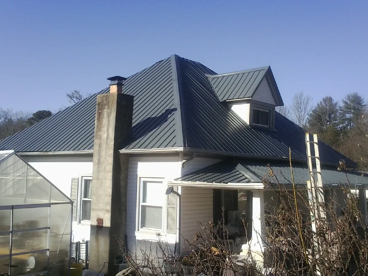 Dark blue standing seam metal roof on a white farmhouse with dormer — Slate & Tile Roof Repair by Roofing Brothers in Mayslick