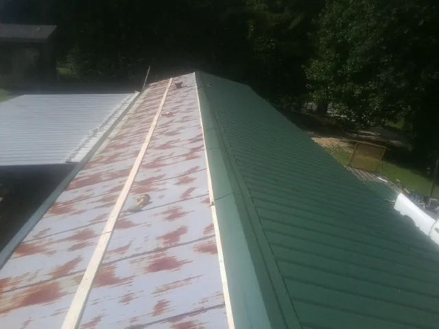 Old rusted panels beside newly installed green metal roofing — Wind Damage Roof Repair by Roofing Brothers in Mayslick