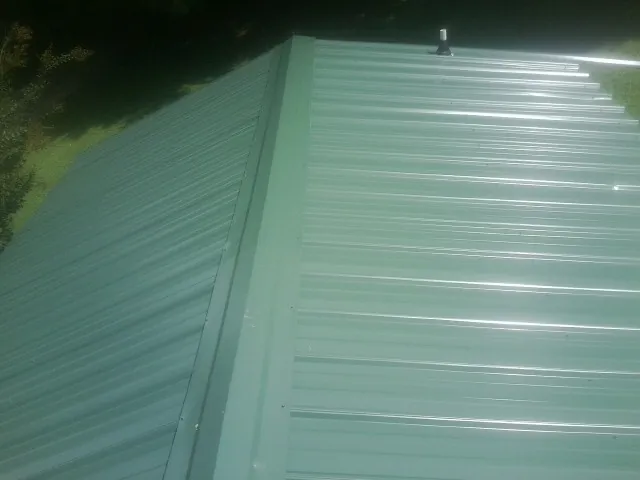 New green metal panels meeting at the ridge of a roof — Flat Roof Repair work by our crew in Mayslick