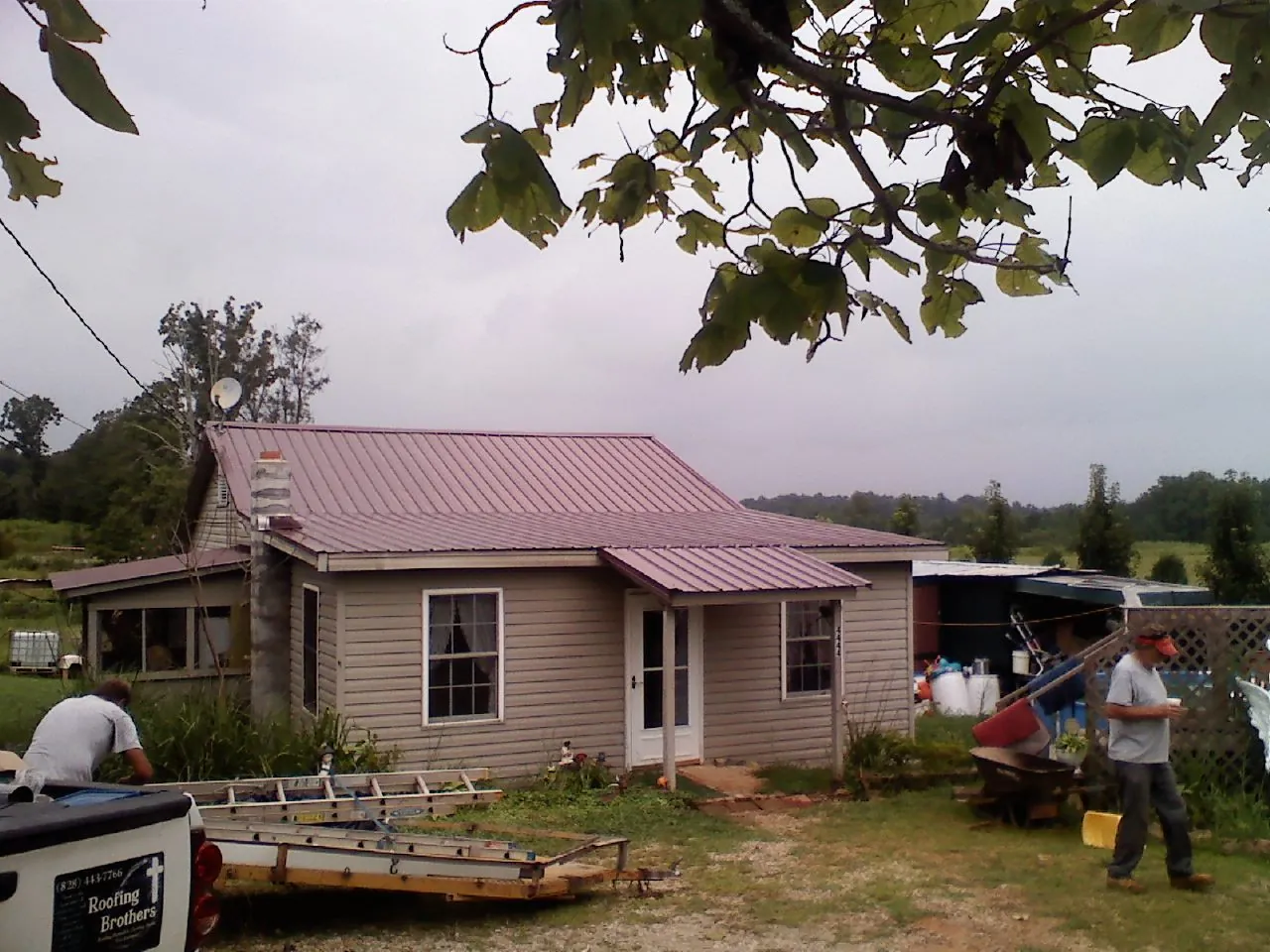 Crew finishing a mauve metal roof on a small farmhouse in Mayslick