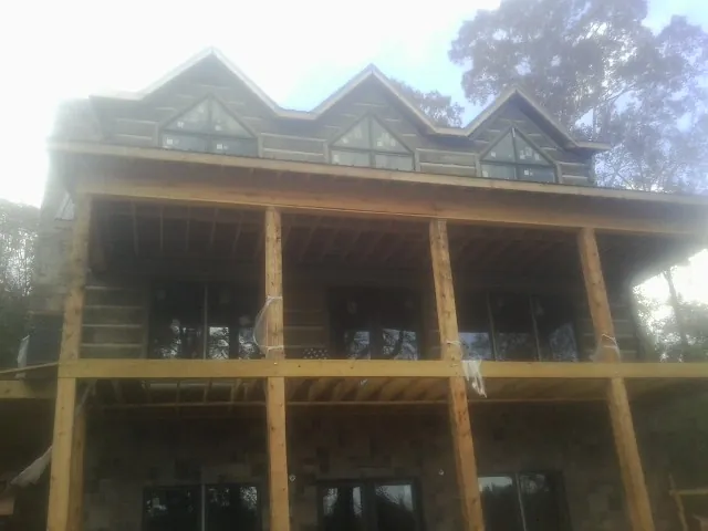Dormers and porch framing on a large log home under construction — Roof Coating work by our crew in Mayslick