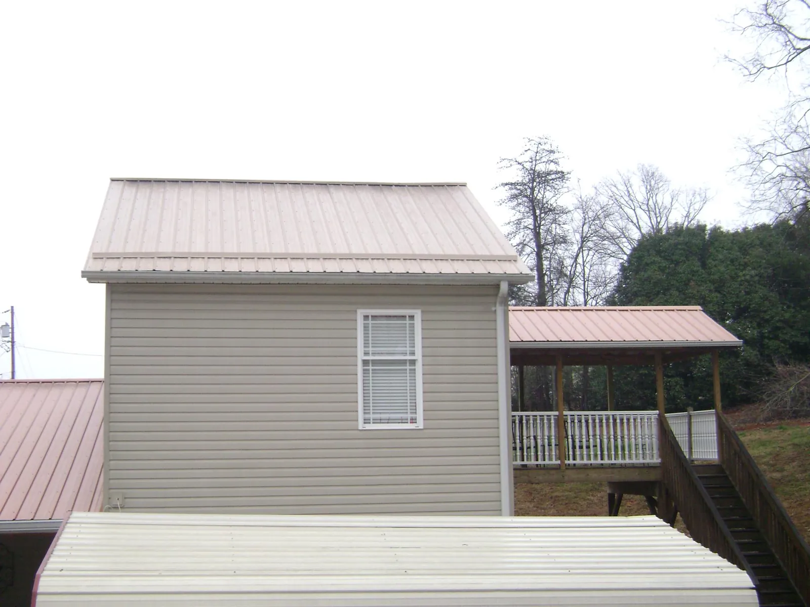 Tan metal roofs on a two story addition and attached porch, from a Roof Replacement job in Mayslick
